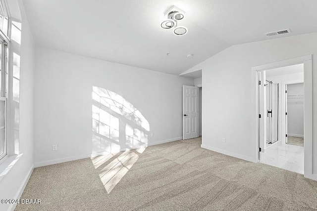 carpeted spare room with lofted ceiling