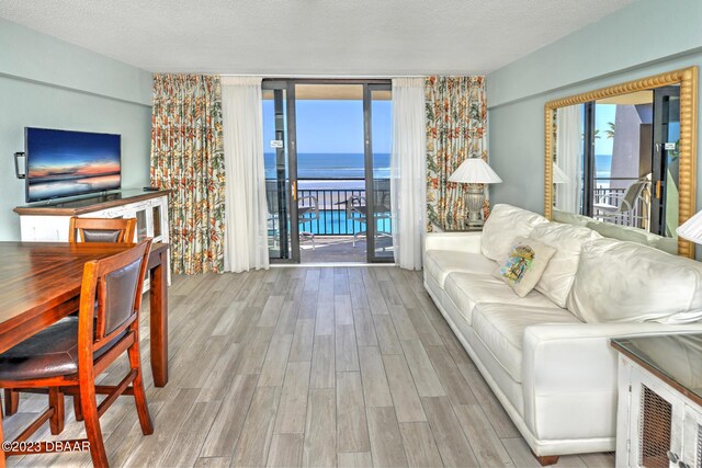 2301 S Atlantic Ave Unit 315, Daytona Beach, FL 32118 - living room with a water view, a textured ceiling, light hardwood / wood-style floors, and a wall of windows