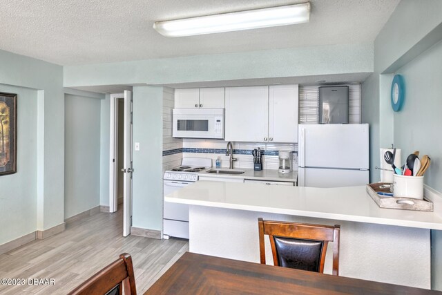 2301 S Atlantic Ave Unit 315, Daytona Beach, FL 32118 - kitchen featuring light hardwood / wood-style floors, white cabinetry, sink, white appliances, and decorative backsplash