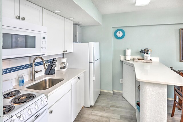 2301 S Atlantic Ave Unit 315, Daytona Beach, FL 32118 - kitchen featuring sink, a breakfast bar area, white cabinetry, light hardwood / wood-style flooring, and white appliances