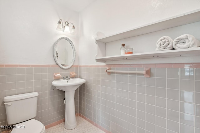 bathroom featuring wainscoting, tile patterned floors, toilet, and tile walls