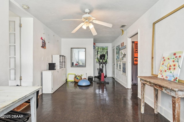 interior space with baseboards, ceiling fan, visible vents, and a textured ceiling