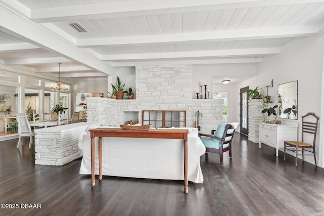 living room with visible vents, an inviting chandelier, a stone fireplace, wood finished floors, and beamed ceiling