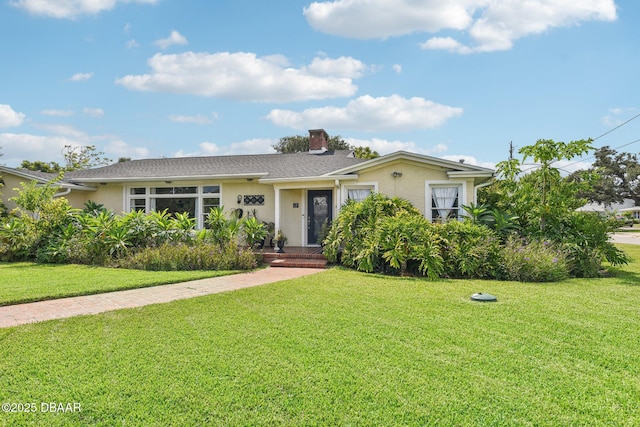 ranch-style house featuring a front yard, a chimney, and stucco siding