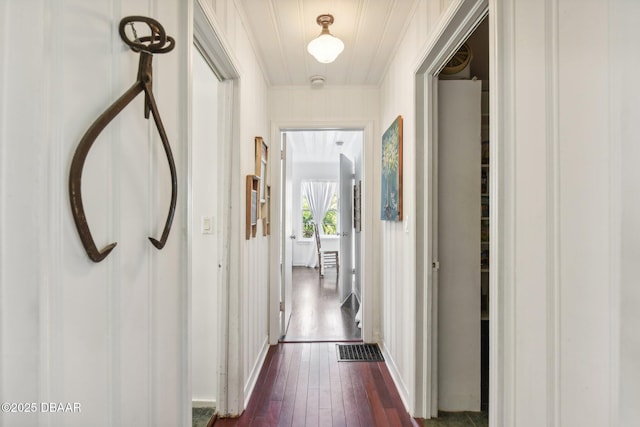 corridor with dark wood-type flooring, visible vents, and ornamental molding