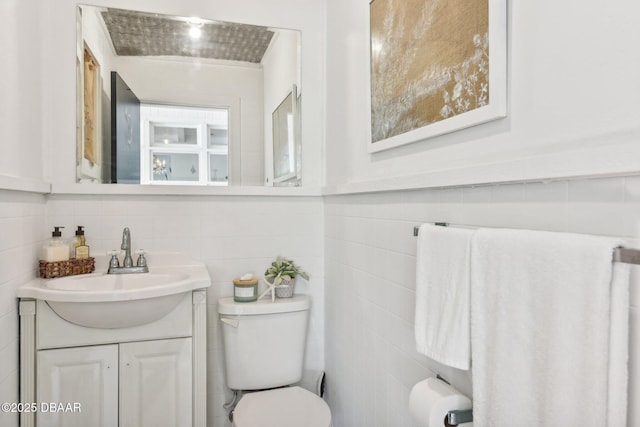 bathroom featuring toilet, tile walls, and vanity