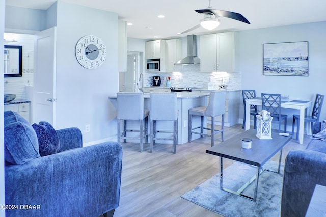 living room with ceiling fan and light hardwood / wood-style flooring