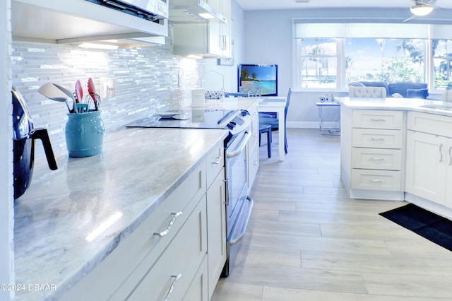 kitchen with light stone countertops, backsplash, extractor fan, white cabinetry, and stainless steel electric range