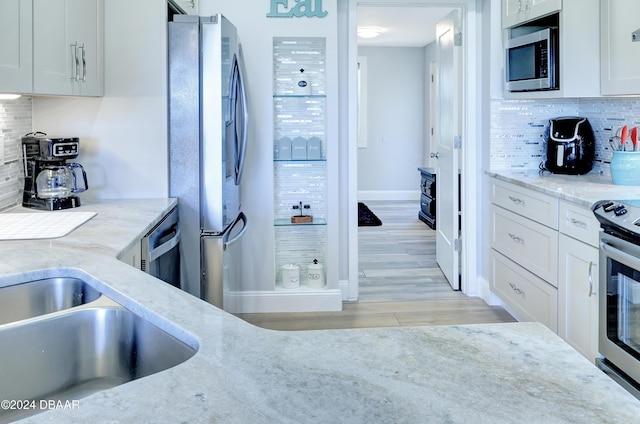 kitchen featuring backsplash, white cabinetry, stainless steel appliances, and light hardwood / wood-style flooring