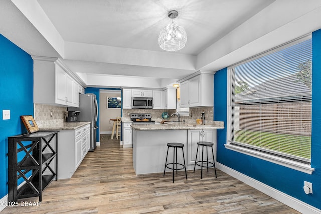 1197 Southfork Ct, Port Orange, FL 32129 - kitchen featuring stainless steel appliances, a peninsula, a chandelier, tasteful backsplash, and white cabinetry