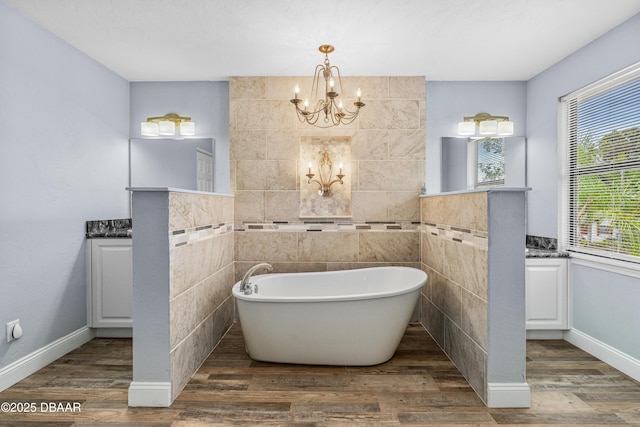 1197 Southfork Ct, Port Orange, FL 32129 - bathroom with a chandelier, a freestanding bath, vanity, wood finished floors, and tile walls