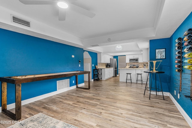 1197 Southfork Ct, Port Orange, FL 32129 - bar area featuring a tray ceiling, appliances with stainless steel finishes, light wood-type flooring, ceiling fan, and ornamental molding