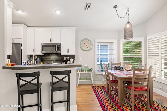 3349 Glenshane Way, Ormond Beach, FL 32174 - kitchen featuring stainless steel appliances, white cabinets, a breakfast bar area, backsplash, and baseboards