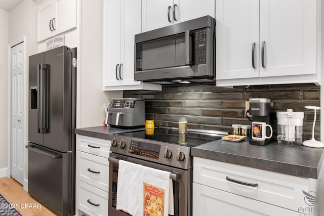 3349 Glenshane Way, Ormond Beach, FL 32174 - kitchen with stainless steel appliances, dark countertops, white cabinetry, and decorative backsplash