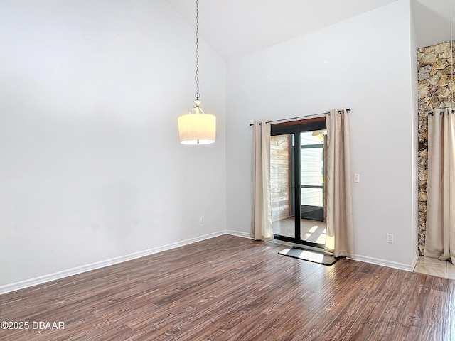 unfurnished room with high vaulted ceiling, baseboards, and wood finished floors