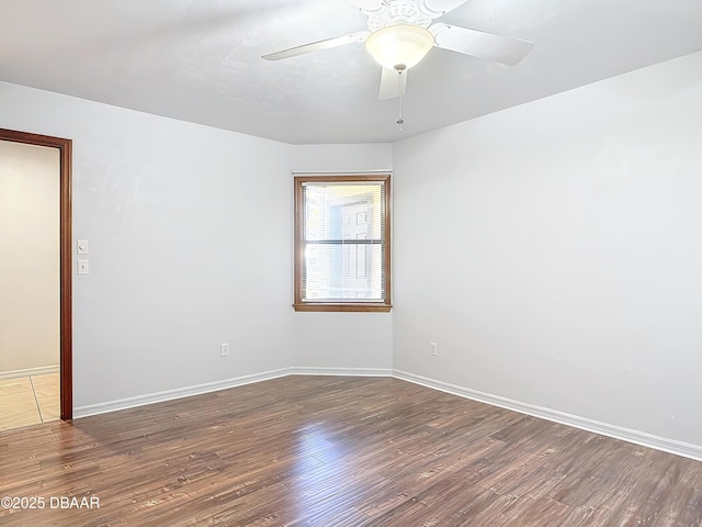 empty room featuring dark wood-type flooring, ceiling fan, and baseboards