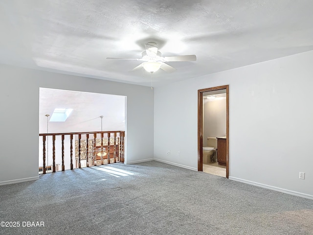 spare room featuring light carpet, baseboards, and a ceiling fan