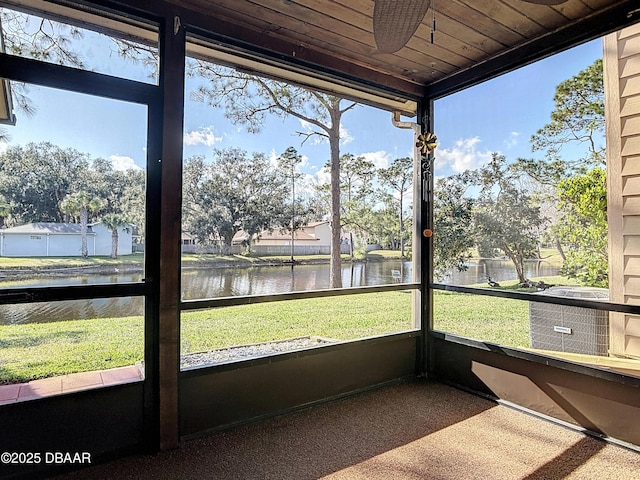 unfurnished sunroom featuring a water view, wood ceiling, and a wealth of natural light