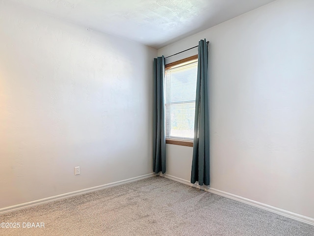 carpeted empty room featuring baseboards