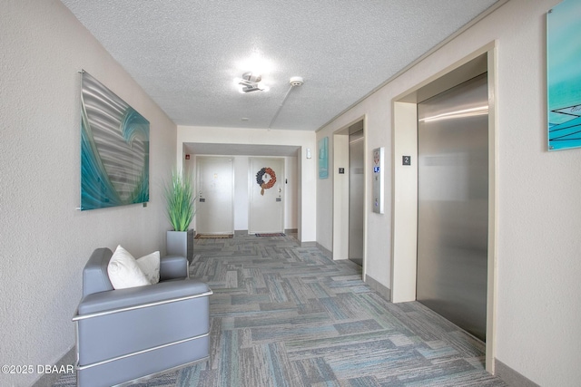 3043 S Atlantic Ave Unit 204, Daytona Beach Shores, FL 32118 - corridor featuring elevator, a textured ceiling, carpet floors, and baseboards