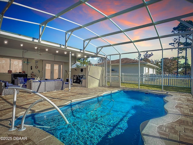 pool at dusk featuring an outdoor hangout area, a patio, french doors, glass enclosure, and ceiling fan