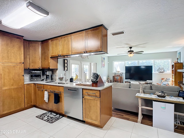 kitchen featuring a textured ceiling, ceiling fan, light tile patterned floors, kitchen peninsula, and stainless steel dishwasher