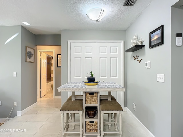 tiled dining room featuring a textured ceiling