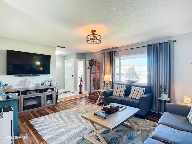 living room with a fireplace, a textured ceiling, and dark hardwood / wood-style floors