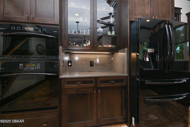 kitchen featuring black appliances, tasteful backsplash, and dark brown cabinetry