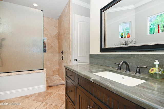 bathroom featuring ornamental molding, tile patterned floors, a tile shower, and vanity