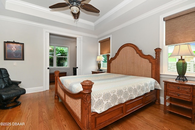 bedroom with ceiling fan, crown molding, a tray ceiling, and hardwood / wood-style floors