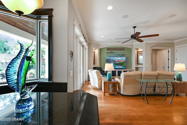 living room with light hardwood / wood-style floors, ceiling fan, and ornamental molding