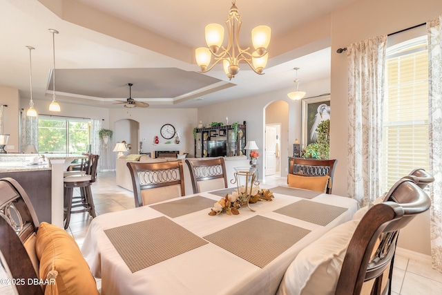 3418 Leonardo Ln, New Smyrna Beach, FL 32168 - dining area with arched walkways, a tray ceiling, light tile patterned flooring, ceiling fan, and a chandelier