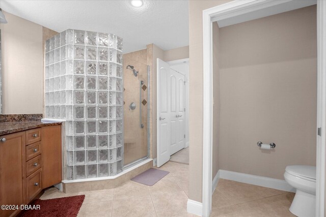 bathroom with toilet, tile patterned floors, vanity, and a shower with door