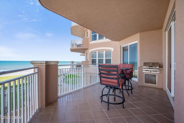 balcony with a grill, a view of the beach, and a water view