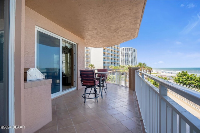 balcony featuring a view of the beach and a water view