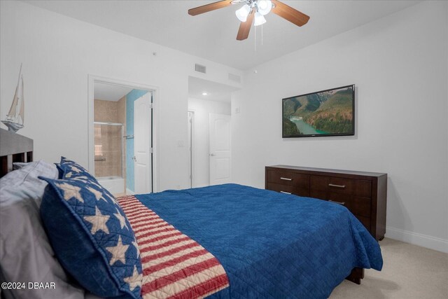 bedroom featuring light carpet, ceiling fan, and connected bathroom