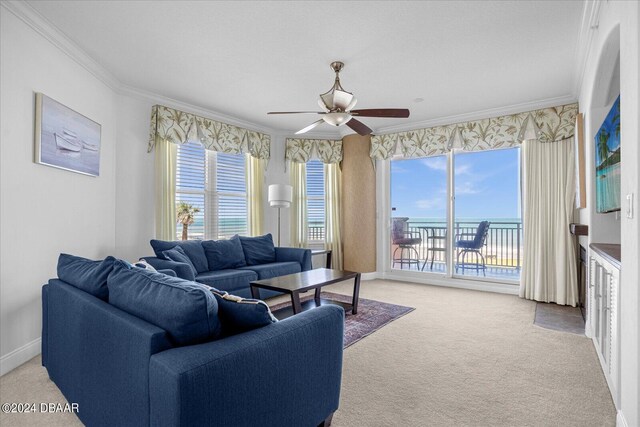 living room featuring ceiling fan, light colored carpet, a water view, and crown molding