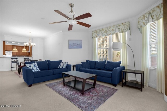 living room with ceiling fan with notable chandelier, crown molding, and light colored carpet