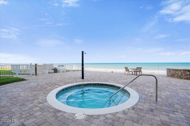 view of swimming pool with a community hot tub, a water view, a beach view, and a patio area