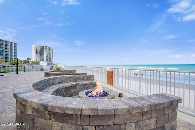 view of patio featuring a beach view, a fire pit, and a water view