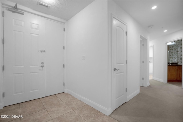 hall featuring light colored carpet and a textured ceiling