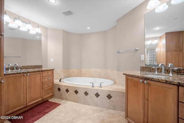 bathroom with tile patterned flooring, vanity, a textured ceiling, and a relaxing tiled tub