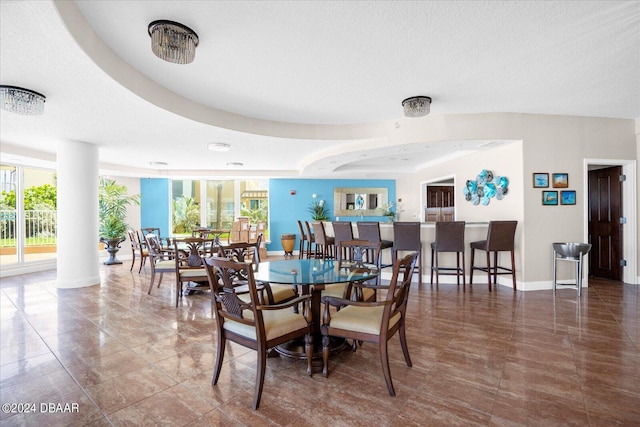 tiled dining area with a wealth of natural light, a textured ceiling, and a raised ceiling