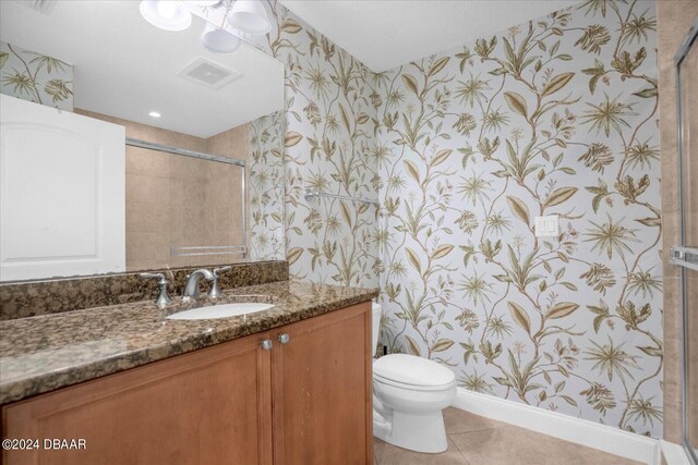 bathroom featuring walk in shower, vanity, toilet, and tile patterned flooring