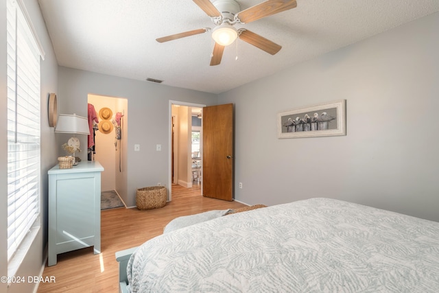 bedroom with multiple windows, a textured ceiling, ceiling fan, and light hardwood / wood-style flooring