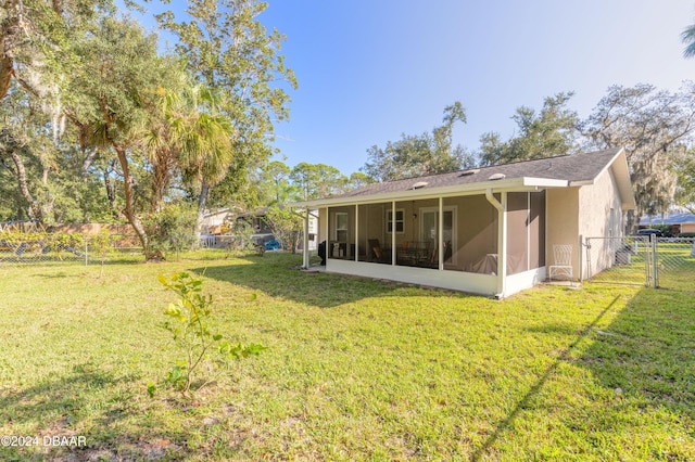 rear view of house featuring a sunroom and a lawn