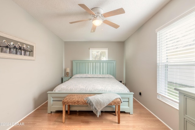 bedroom featuring ceiling fan, a textured ceiling, and light hardwood / wood-style floors