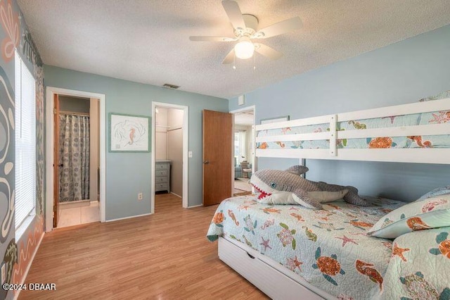 bedroom featuring light hardwood / wood-style floors, ensuite bathroom, ceiling fan, a closet, and a spacious closet