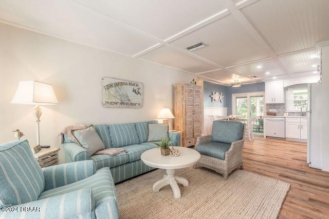 living room featuring light hardwood / wood-style flooring, sink, and coffered ceiling